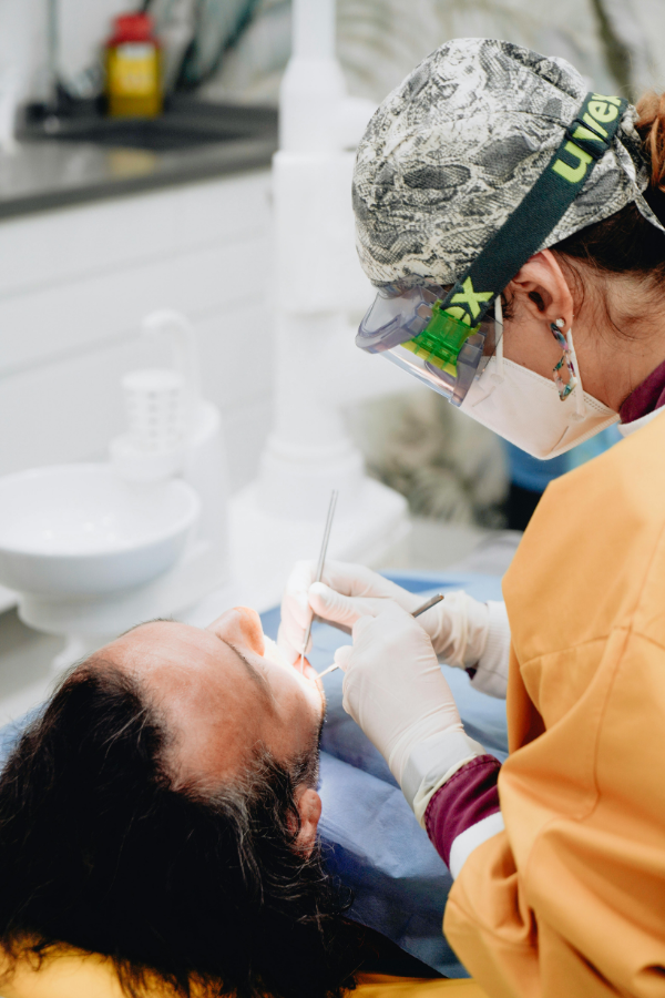 Periodontist in blue gloves examining a patient's gums for gum disease treatment at Colorado Gum Care in Broomfield, CO